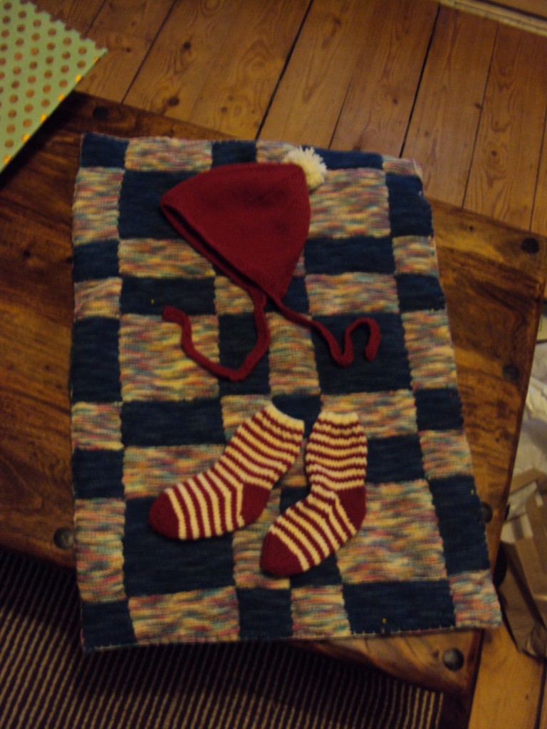 A patchwork blanket made from leftover sock yarn (WHY do people knit socks! Not even I love craft that much). Plus, Christmassy baby hat and socks. For sh*ts and giggles.